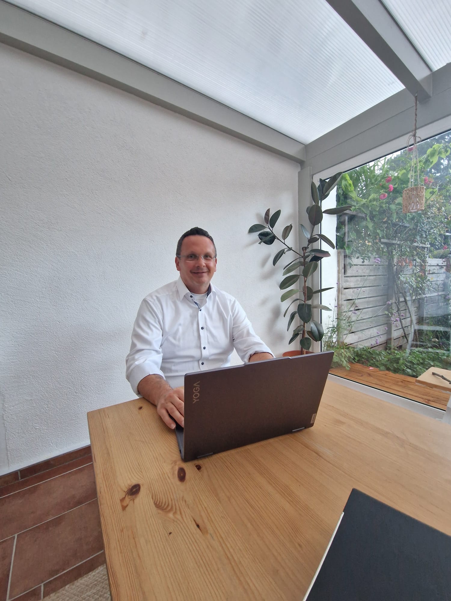 Tobias stellt eine Baufinanzierung Neuss zusammen und sitzt mit Notebook am Tisch